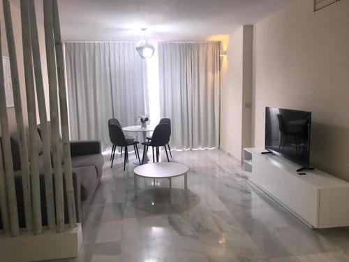 sala de estar con TV, mesa y sillas en Apto EN JARDINES DEL PUERTO, en Marbella