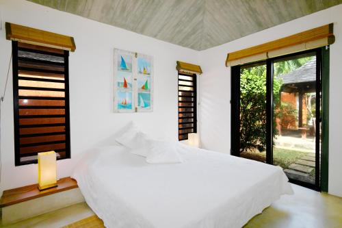 a white bedroom with a white bed and windows at Elegant Villa Bali style in Blue Bay in Blue Bay