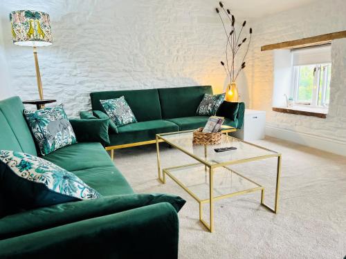 a living room with a green couch and a coffee table at The Stables - Luxury Holiday Cottage in Welsh Newton Common