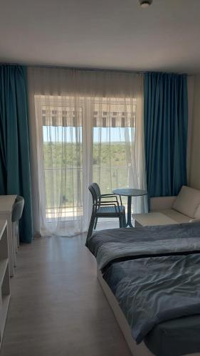 a bedroom with a bed and a table and window at Camera de închiriat Blaxy Premium Resort in Olimp