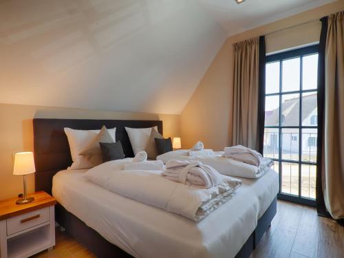德蘭斯克的住宿－Reetland am Meer - Luxus Reetdachvilla mit 3 Schlafzimmern, Sauna und Kamin F18，一间卧室设有两张床和大窗户