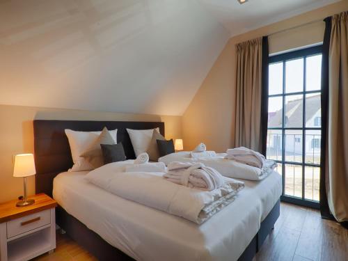 ein Schlafzimmer mit zwei Betten und einem großen Fenster in der Unterkunft Reetland am Meer - Luxus Reetdachvilla mit 3 Schlafzimmern, Sauna und Kamin F18 in Dranske