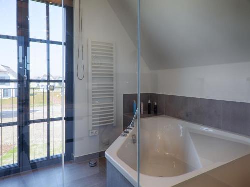 eine große weiße Badewanne im Bad mit Fenster in der Unterkunft Reetland am Meer - Luxus Reetdachvilla mit 3 Schlafzimmern, Sauna und Kamin F18 in Dranske