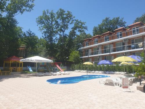 a swimming pool with chairs and umbrellas next to a building at Hotel Maria in Kiten