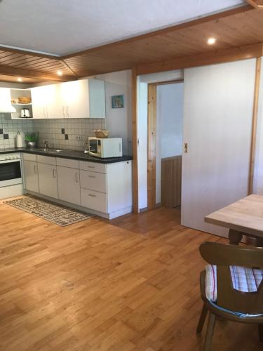 a kitchen with white cabinets and a wooden floor at Haus Petra in Oberjoch