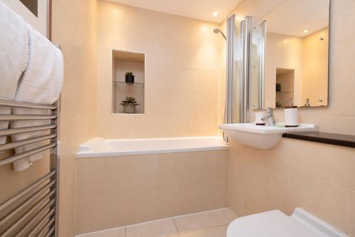 a bathroom with a sink and a tub and a toilet at JOIVY Luxury Flat near Edinburgh Castle in Edinburgh