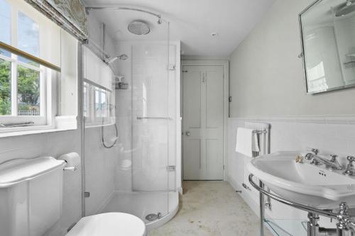 a white bathroom with a shower and a sink at Poplar Cottage, Budleigh Salterton in Budleigh Salterton