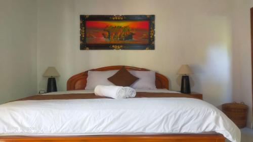 Un dormitorio con una cama blanca con una foto en la pared en Serongga guest house, en Lebih