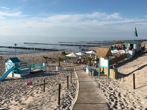 a beach with a wooden pathway and a playground at Ferienwohnung Dünenhopser in Rostock