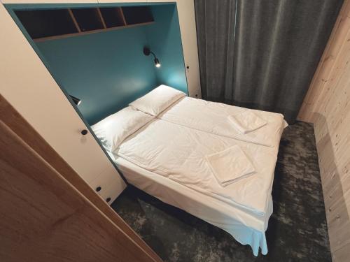 a small bed in a small room with a blue wall at Jūros 40 in Šventoji