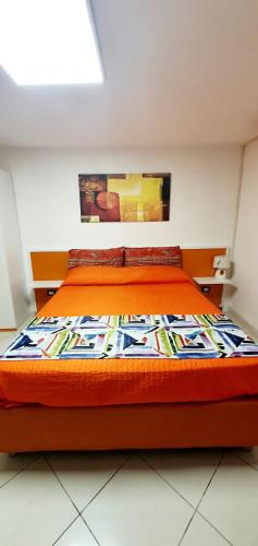 a bed with an orange bedspread in a room at Bed& Breakfast G&G in Porto Garibaldi