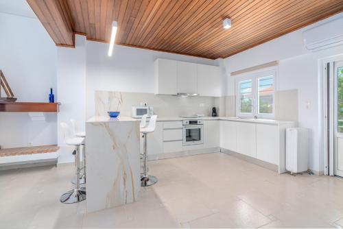 a kitchen with white cabinets and a wooden ceiling at COSTA VASIA Seaside Suites and Apartments in Vrahati