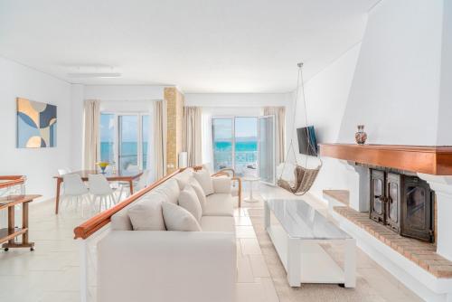 a living room with a white couch and a fireplace at COSTA VASIA Seaside Suites and Apartments in Vrachati