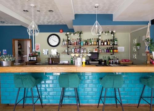 a bar with blue walls and bar stools at Loch Ness Drumnadrochit Hotel in Drumnadrochit