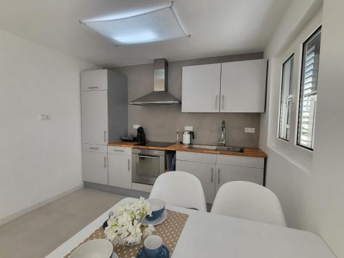 een keuken met witte kasten en een tafel en stoelen bij Modern Apartment Tara with Parking in Malinska