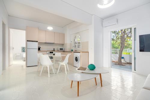 a white kitchen with a table and white chairs at COSTA VASIA Seaside Suites and Apartments in Vrahati