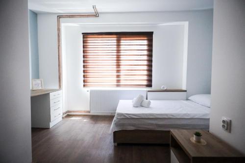 a white bedroom with a bed and a window at Domaćin Komšijska Gostiona in Zrenjanin