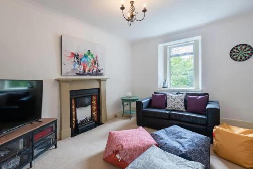 a living room with a couch and a television at 5 bedrooms sleeps 10-12 free wifi & parking garden in Lundin Links