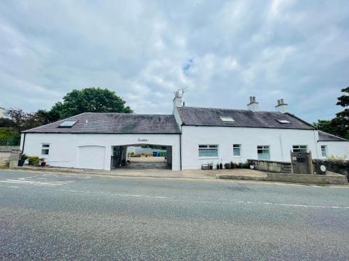a white building with a large doorway on a street at 5 bedrooms sleeps 10-12 free wifi & parking garden in Lundin Links