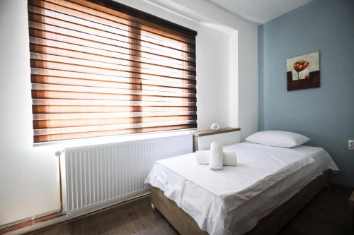 a bedroom with a bed and a window with blinds at Domaćin Komšijska Gostiona in Zrenjanin