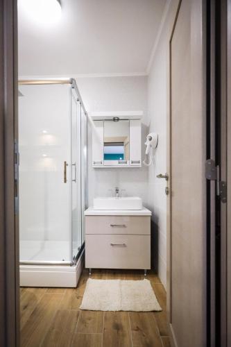 a white bathroom with a sink and a shower at Domaćin Komšijska Gostiona in Zrenjanin
