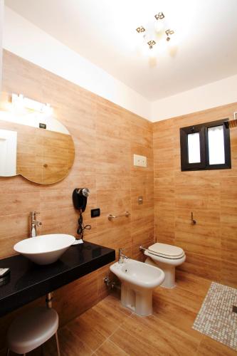 a bathroom with two sinks and a toilet and a mirror at Momi's Hotel in Cavarzere