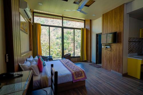 a hotel room with a bed and a large window at Haut Monde Hill Stream Resort and Spa in Dehradun
