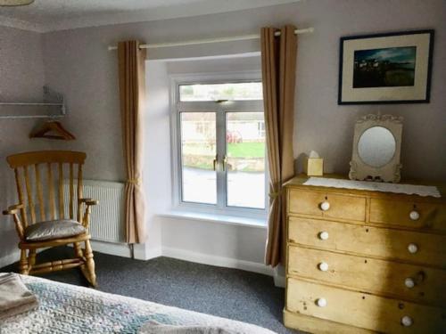 a bedroom with a dresser and a window with a chair at The Old Gasworks in Milverton
