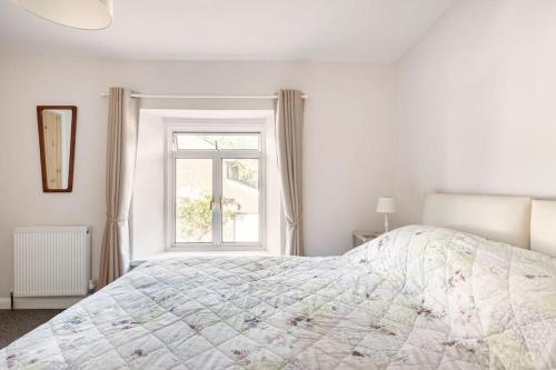 a white bedroom with a bed and a window at The Old Gasworks in Milverton