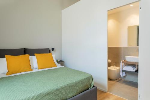 a bedroom with a bed with yellow pillows and a sink at Mori's Rooms in Palermo