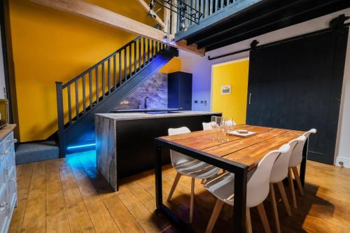 a dining room with a wooden table and white chairs at The Eden Warehouse - Gold Apartment, sleeps 5 in Southport