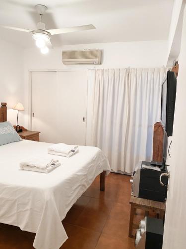 1 dormitorio con 1 cama blanca y TV en Departamento con estilo salteño en Salta