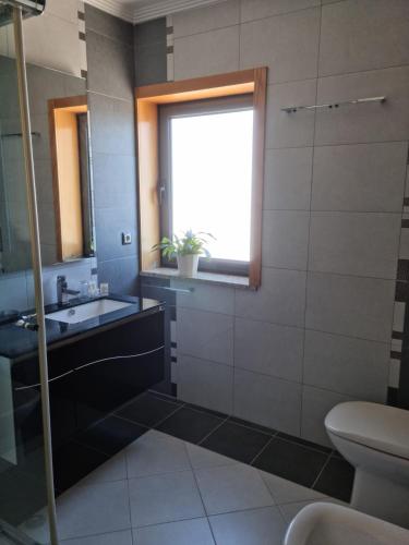 a bathroom with a sink and a toilet and a window at Florindo - Lafões Guest House in Oliveira de Frades