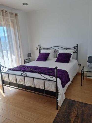 a bedroom with a large bed with purple pillows at Florindo - Lafões Guest House in Oliveira de Frades