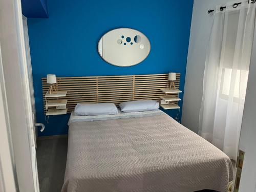 een blauwe slaapkamer met een bed en een klok aan de muur bij CORNELIA´S HOME 4 Primera linea de playa in Los Cristianos