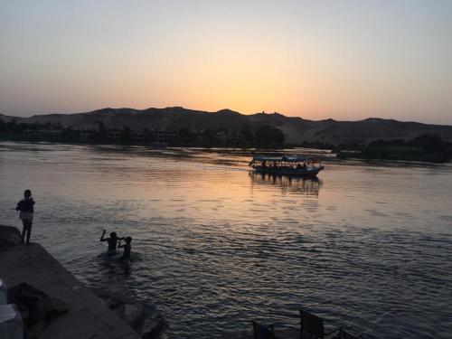 a group of people standing in the water with a boat at Go Inn Backpackers in Aswan