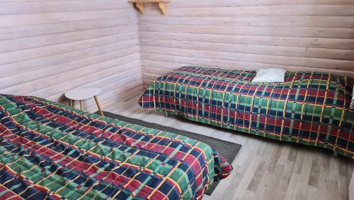 two beds in a room with wooden walls at Youth Center Vasatokka in Inari