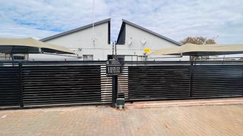 a black fence with a sign in front of a building at Zinathi Lodge in Lebowakgomo