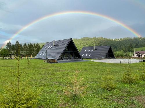 a rainbow over two barns in a field at Treeline Cabins in Cădăreşti