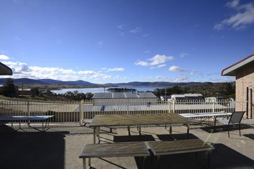 a picnic table and chairs on a patio with a view of the water at Alpine Resort Motel in Jindabyne