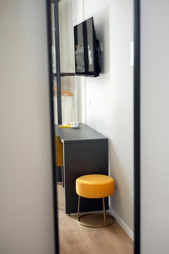 a room with a desk and a yellow stool at Mori's Rooms in Palermo