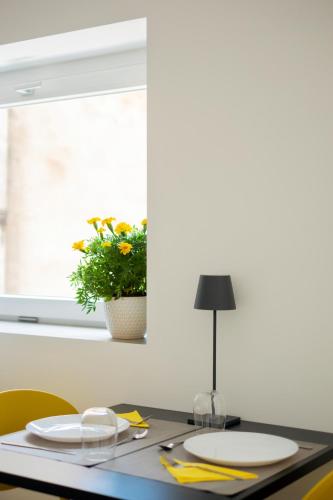 a table with plates and a plant in a window at Mori's Rooms in Palermo