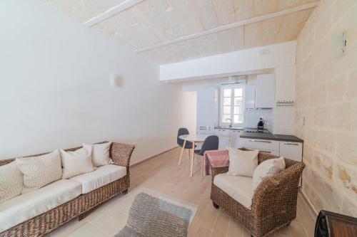 ein Wohnzimmer mit einem Sofa und Stühlen sowie eine Küche in der Unterkunft Central Valletta Townhouse-Hosted by Sweetstay in Valletta