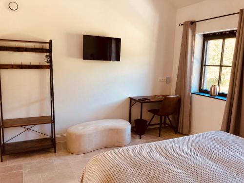 a bedroom with a bed and a desk with a television at De Molenhoeve in Voeren