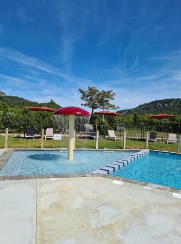 - une piscine avec des parasols et des chaises rouges dans l'établissement Safaritent Glamping de L'Olivigne, à Bize-Minervois