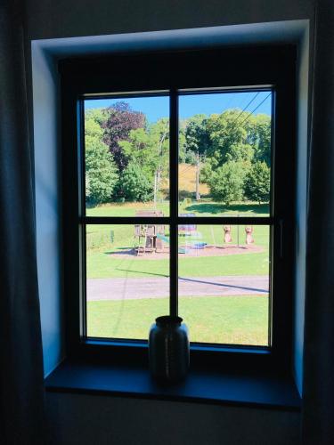a window with a view of a park seen through it at De Molenhoeve in Voeren