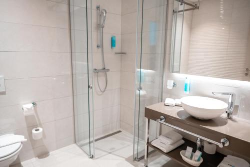 a bathroom with a shower and a sink and a toilet at Hotel Seven in Villach