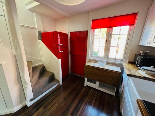 a kitchen with a red refrigerator and a wooden floor at Bridewell Cottage in the heart of Tenterden - Pass The Keys in Tenterden