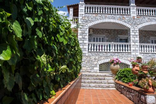 a stone wall with plants and flowers on a patio at Amalia Apartments in Stoupa