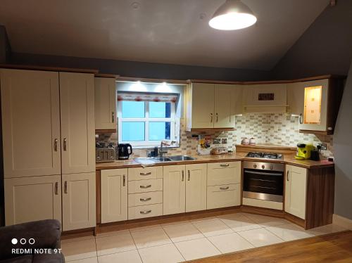 eine Küche mit weißen Schränken und einem Fenster in der Unterkunft Cosy 1 bedroom cottage, Ideal quiet getaway. in Creeslough